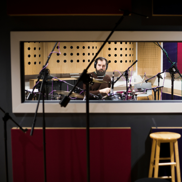 Student plays an instrument in a recording booth.
