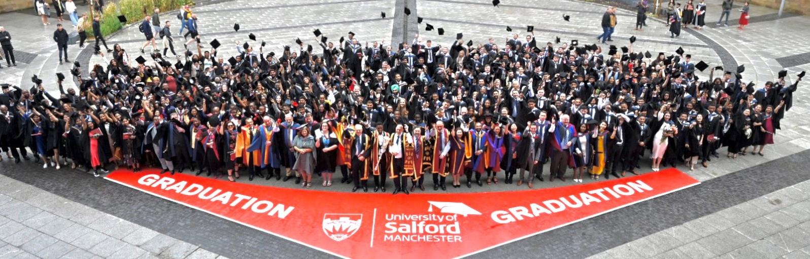 Graduates posing for photograph outside The Lowry Theatre at Salford Quays