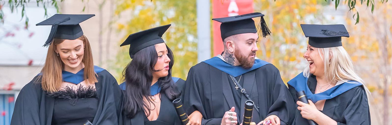 Four graduates celebrating on campus