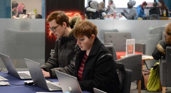 Two students working on laptops in the Library